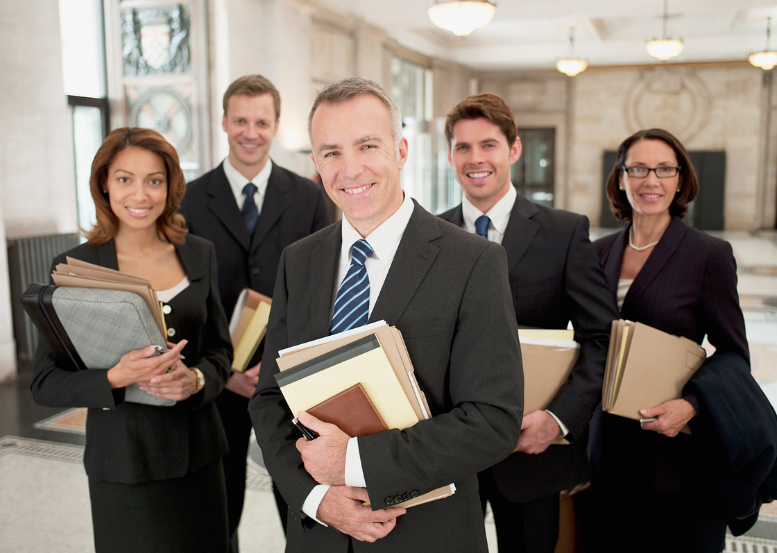 Group of professionals holding folders, smiling confidently.