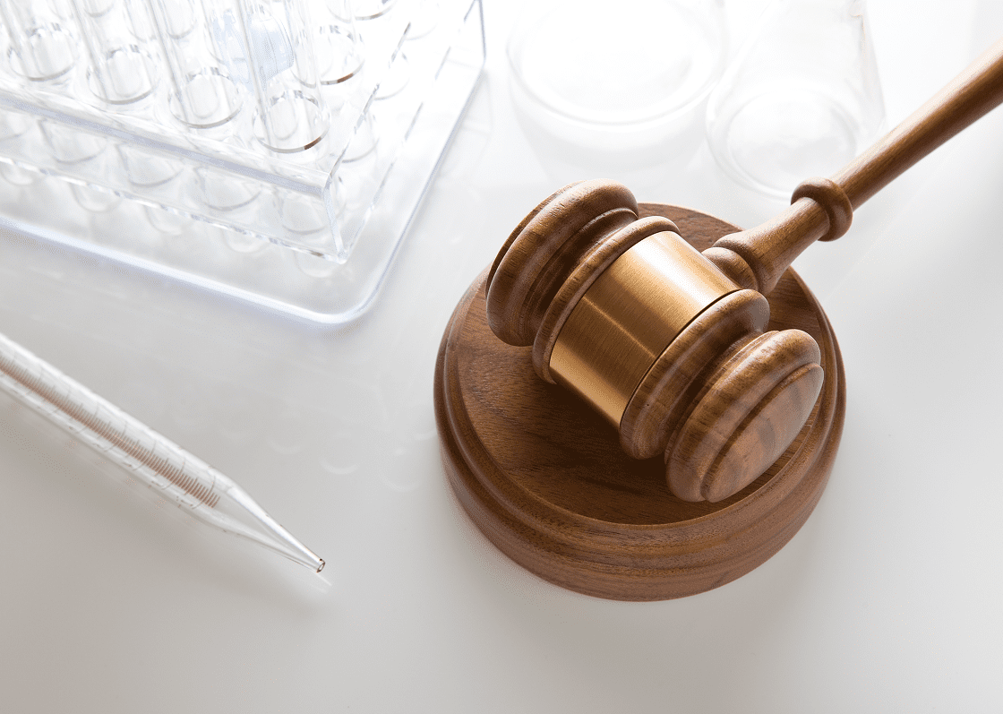 Gavel and lab equipment on white surface.